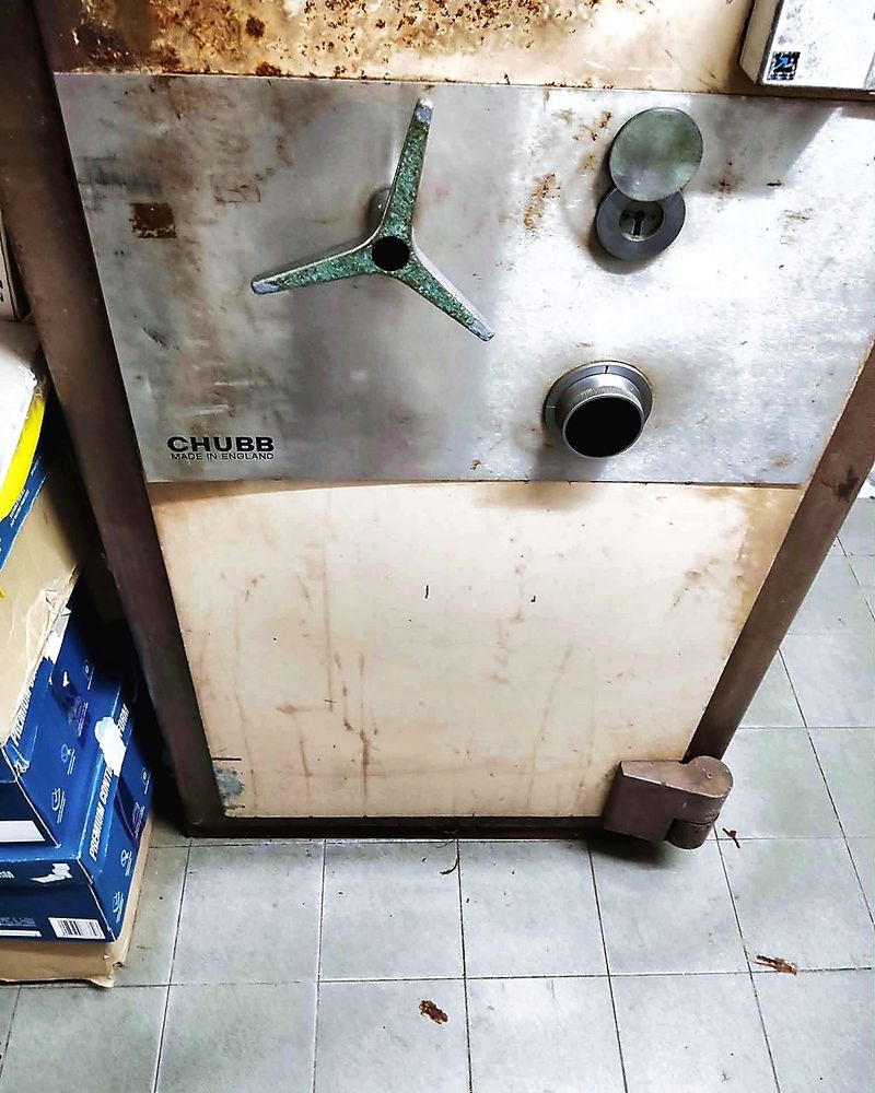 Older Chubb safe with a spoked handle, combination dial and key lock in a Singapore storeroom