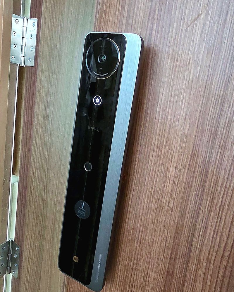 Slim black digital door lock with camera installed on a wooden door